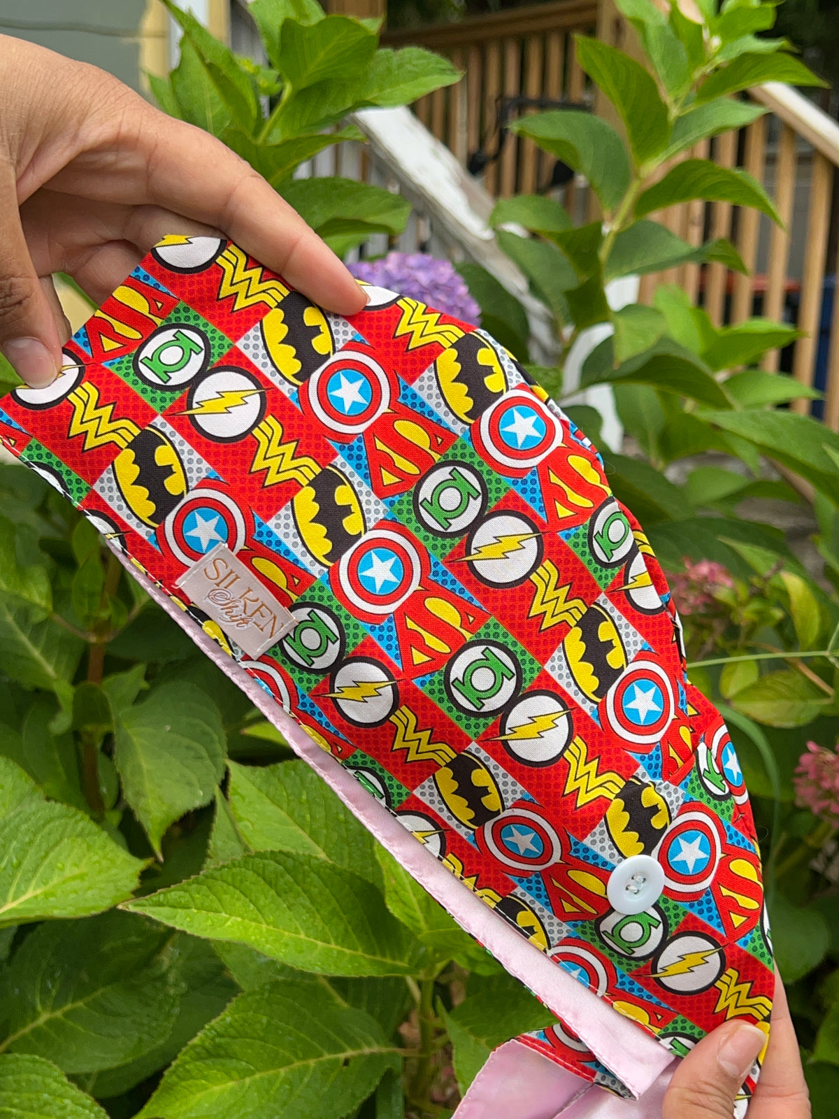 Colorful superhero emblem-print scrub cap with pale pink satin lining and a white side button