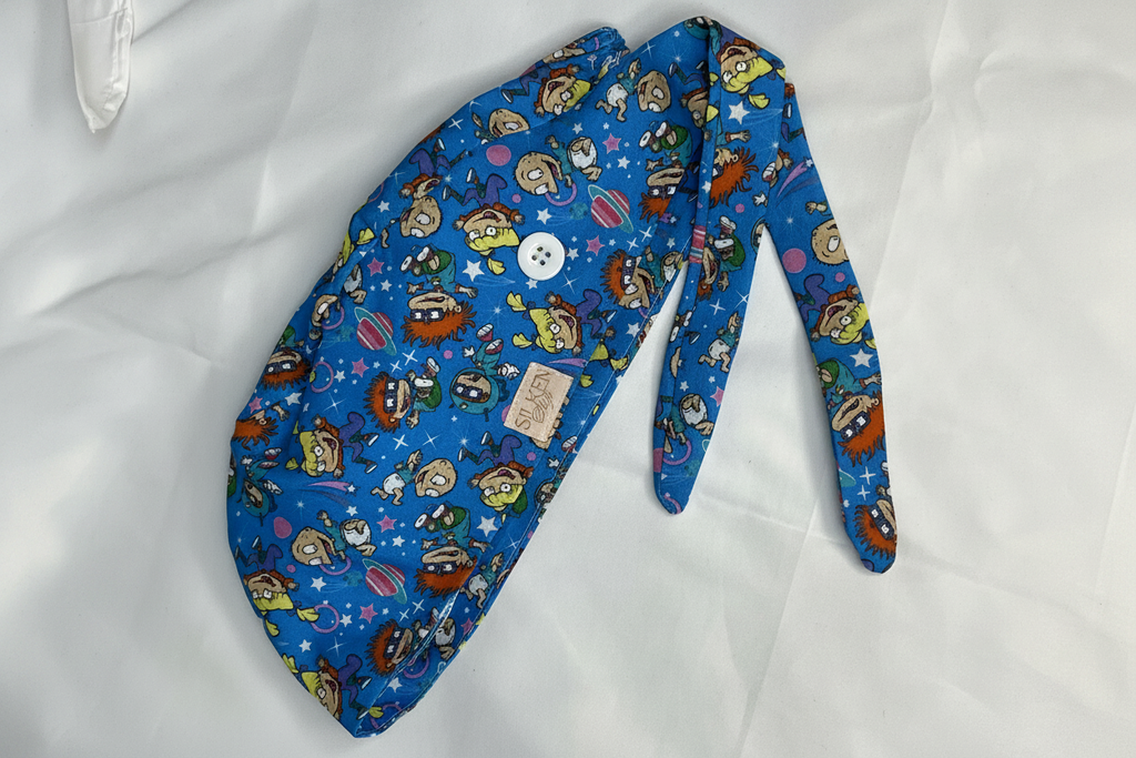 Rugrats space scrub cap on white background showing full galaxy print with tie-back and button loop
