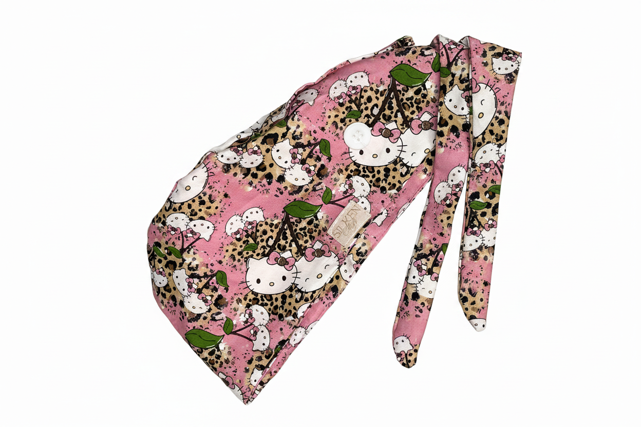 Hello Kitty cheetah print scrub cap on white background showing full pink cheetah print with tie-back and button loop